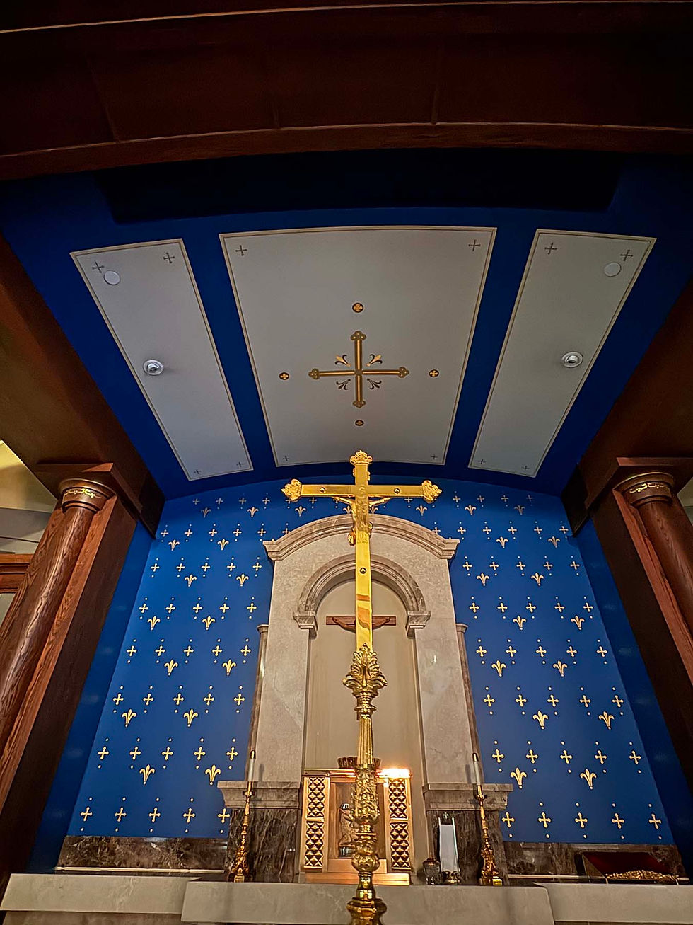The altar at Holy Trinity Catholic Parish, featuring a gold crucifix and blue wallpaper